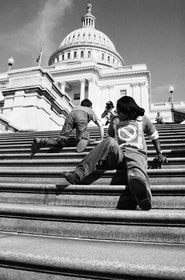 black and white A man and a women with disabilities abandon their mobility aids to climb up the Capitol steps.