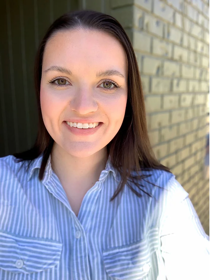 A headshot of Emma Shipley wearing a blue and white striped button-up shirt